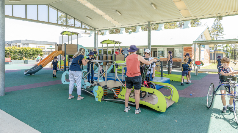 Children and carers playing with inclusive seasaw at Port Macquarie Public School Inclusive Playground