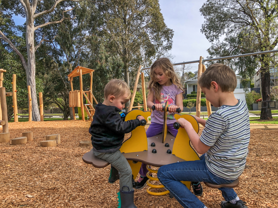 Three children rocking on a springer